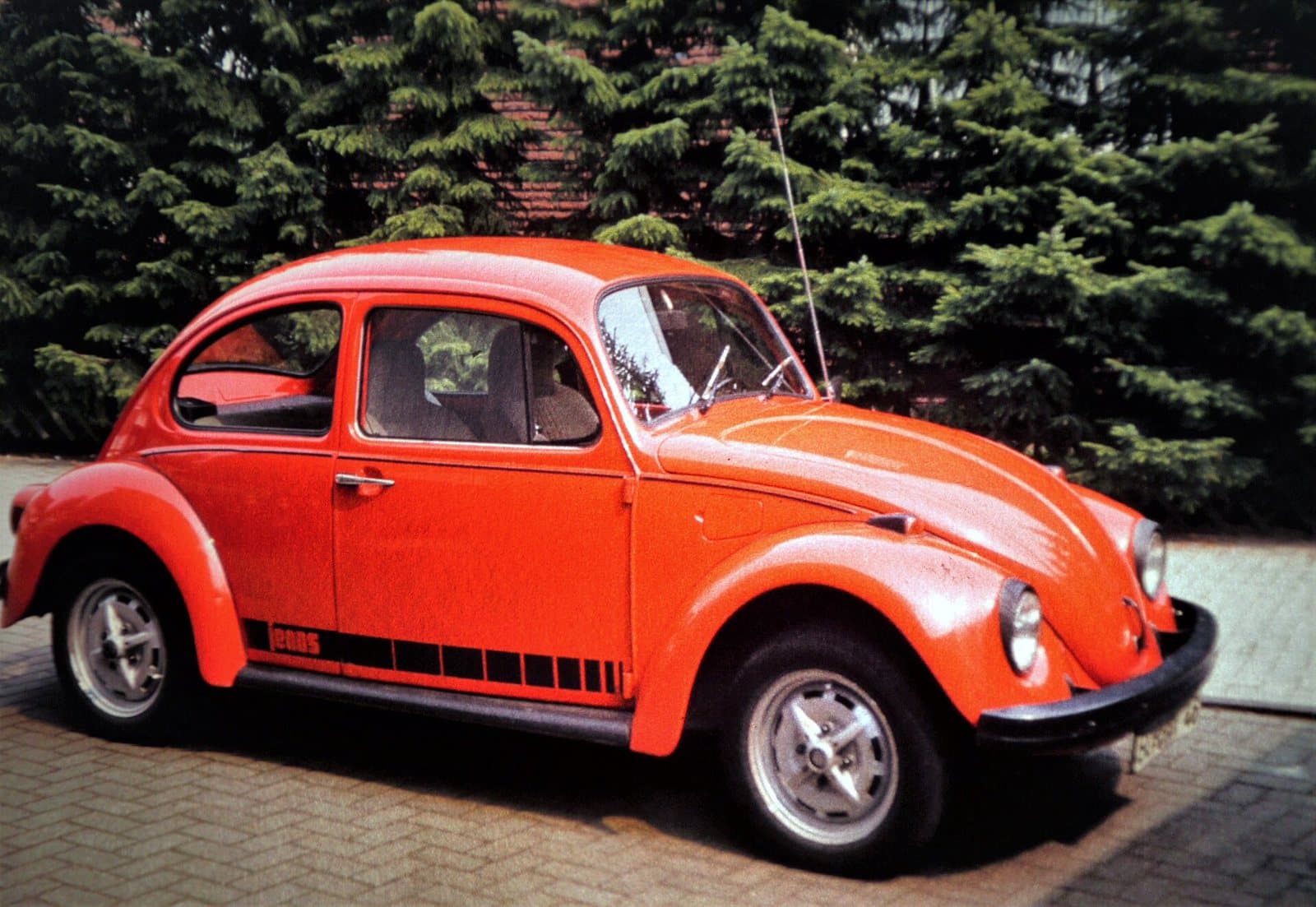 Ein orangefarbener VW Käfer Sondermodell Jeans auf silbernen Stahl-Sportfelgen