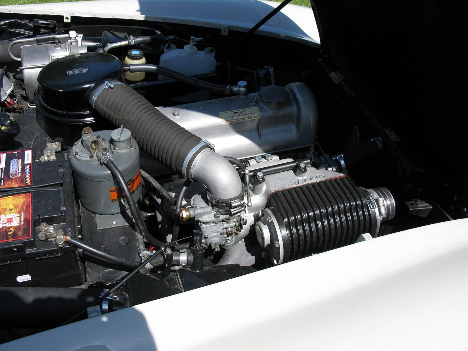 Ein Judson-Kompressor mit der Aufschrift Supercharged im Motorraum eines Mercedes 190 SL