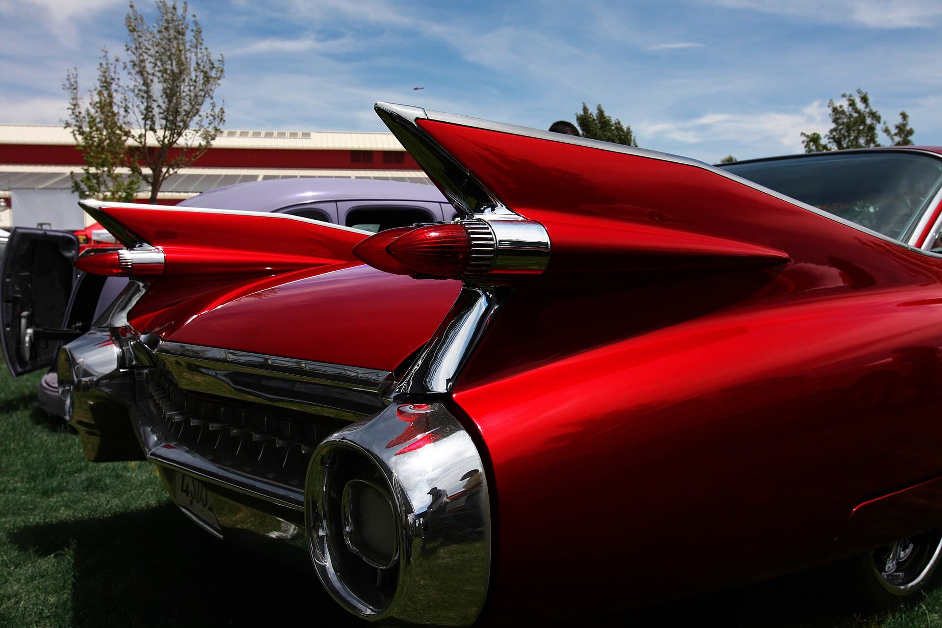 Die Flosse des Jahrgangs 1959 mit ihren 2 Raketenleuchten. Höher kam Detroit nie wieder. Foto: Rennett Stowe, Wikimedia Commons, CC BY 2.0, skaliert. Die Heckflosse eines roten Cadillac von 1959 mit den beiden Raketenleuchten in Nahaufnahme