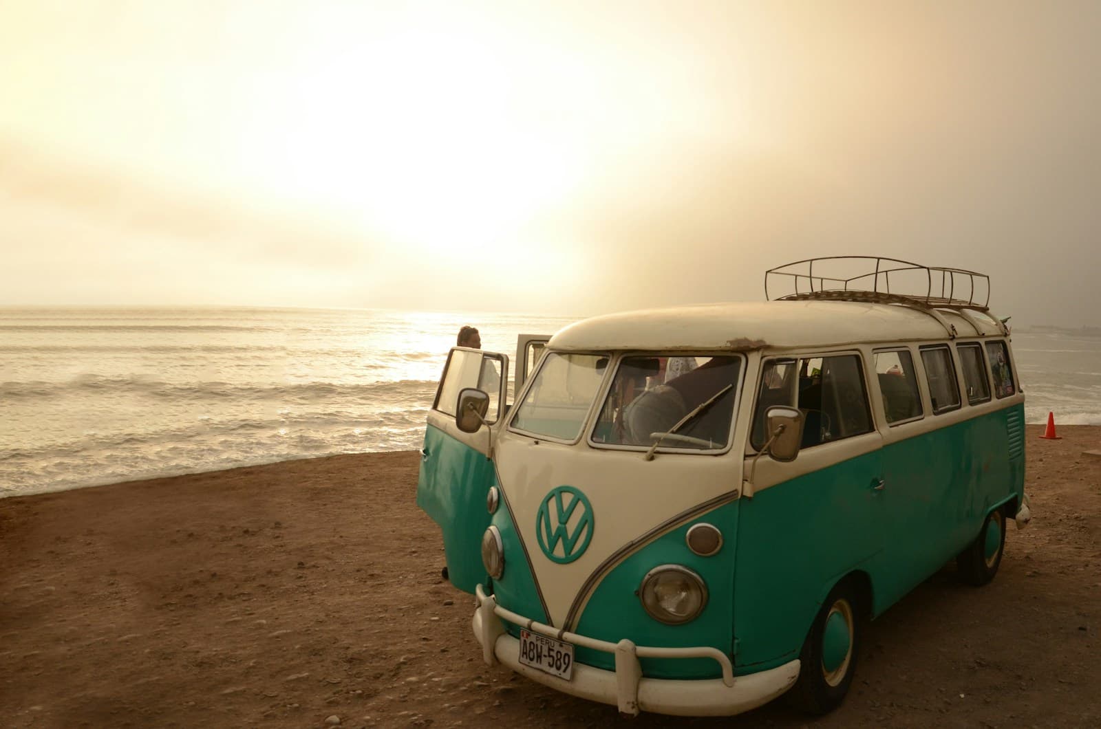 Der Bus, um den es geht: ein T1 im Gegenlicht am Wasser. Dieses Stimmungsbild entstand nicht auf Fehmarn. Ein VW T1 in Türkis und Weiß am Strand, die tiefstehende Sonne dahinter