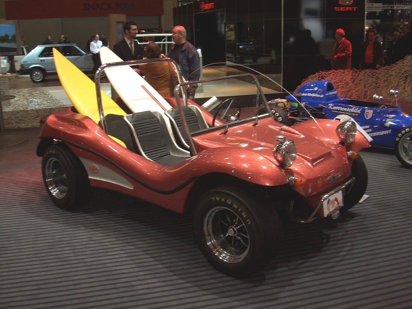 Ein EMPI Imp von 1968 auf der Techno-Classica 2008 in Essen. Foto: Detectandpreserve, Wikimedia Commons, CC BY-SA 3.0, skaliert. Ein rotbrauner EMPI Imp von 1968 mit Metalflake-Lack und Surfbrettern auf einer Messe