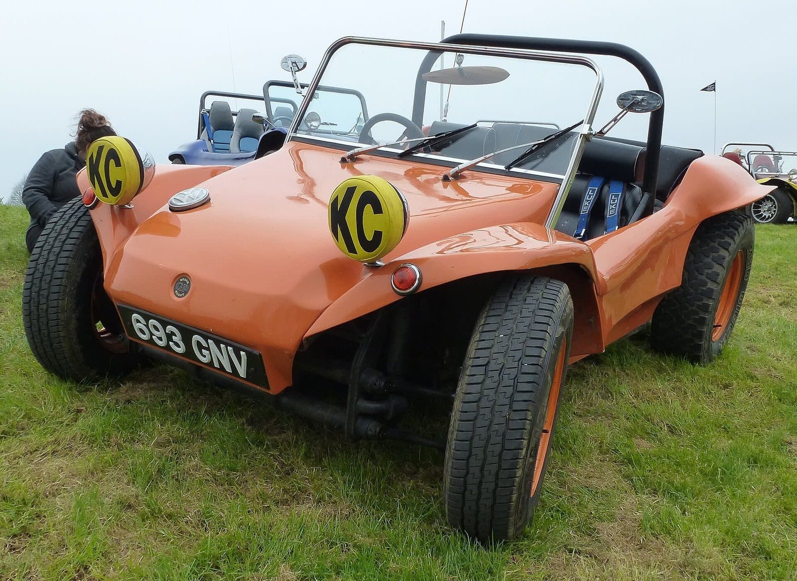 Ein GP Buggy aus England. Foto: Buch-t, Wikimedia Commons, CC BY-SA 3.0 de, skaliert. Ein orangefarbener GP Buggy mit gelben Scheinwerferkappen und britischem Kennzeichen auf einer Wiese