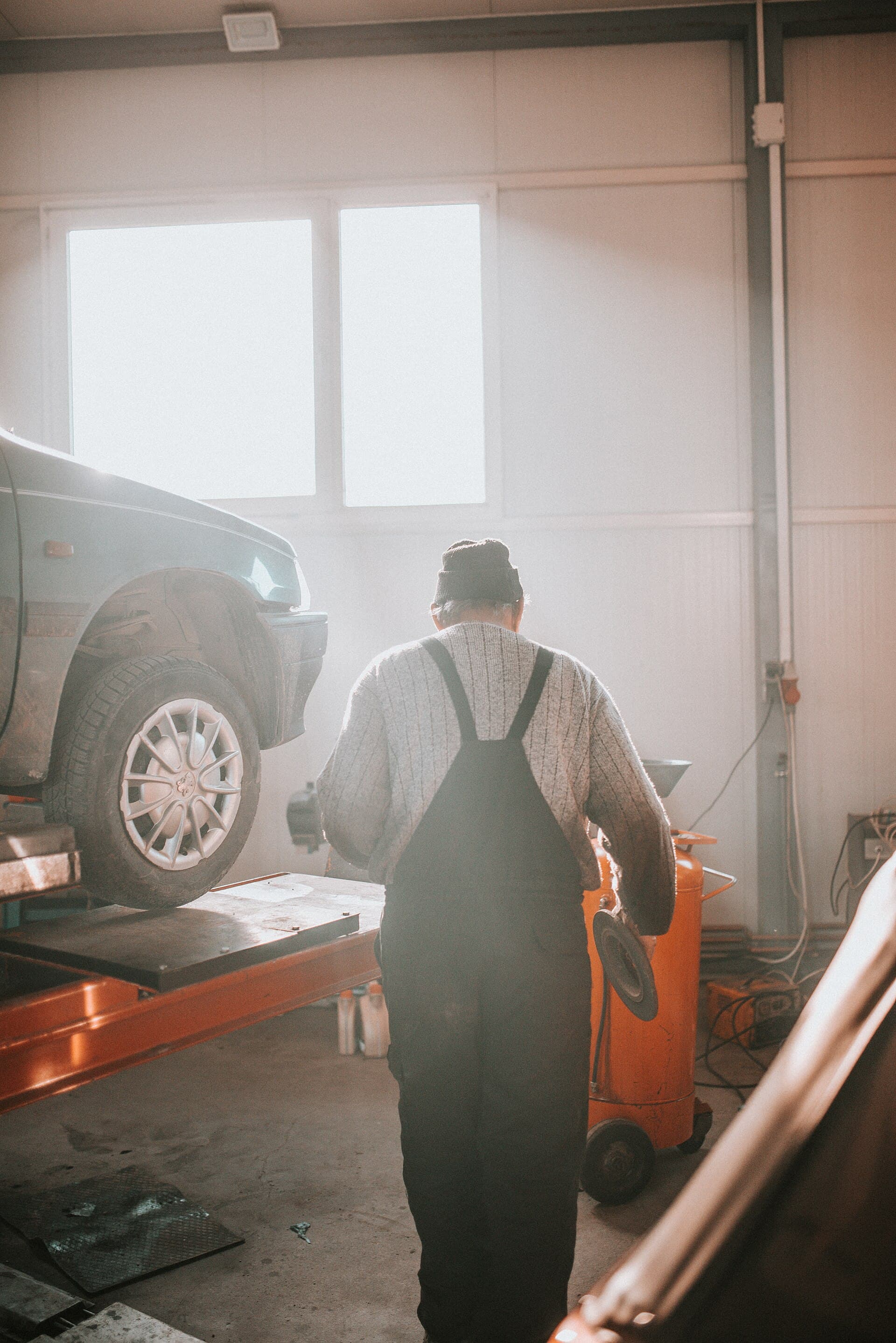 Die Bühne entscheidet: Erst von unten zeigt sich, ob frischer Unterbodenschutz Arbeit oder Rost verdeckt. Foto: Shixart1985, Wikimedia Commons, CC BY 2.0, skaliert. Ein Mechaniker steht unter einem Auto auf der Hebebühne in einer Werkstatt