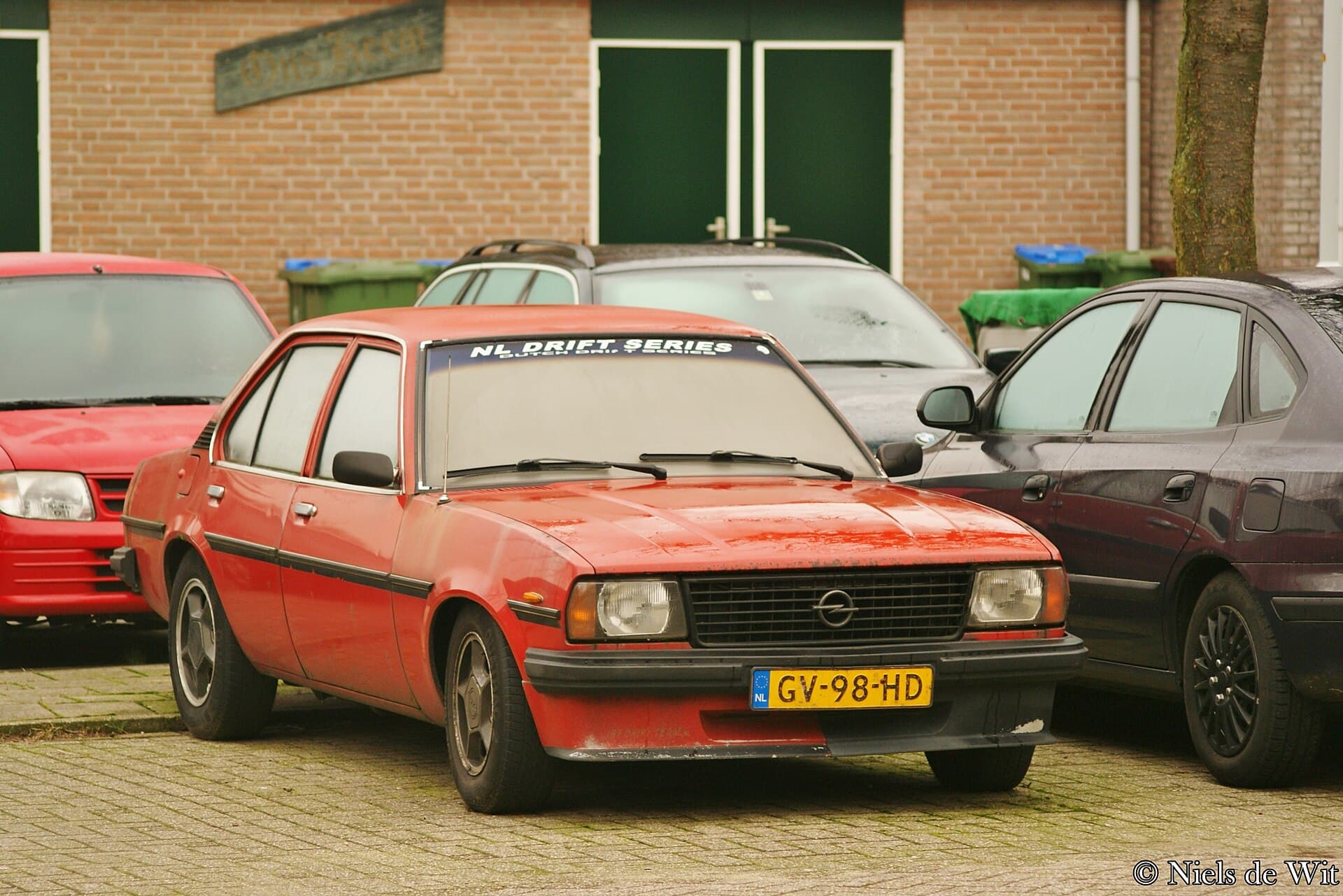 Ein SR von 1981, nach der Modellpflege: schwarze Kunststoffstoßfänger und grauer Grill. Ob die Streifen und die Instrumente original sind, sagt nur der Brief. Foto: Niels de Wit, Wikimedia Commons, CC BY 2.0, skaliert. Ein roter Opel Ascona B SR von 1981 mit den schwarzen Kunststoffstoßfängern der Modellpflege
